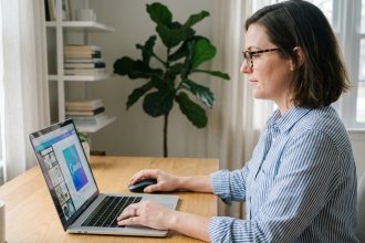 Femme concentrée utilisant Canva sur son ordinateur dans un bureau lumineux