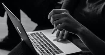 grayscale photo of person using MacBook